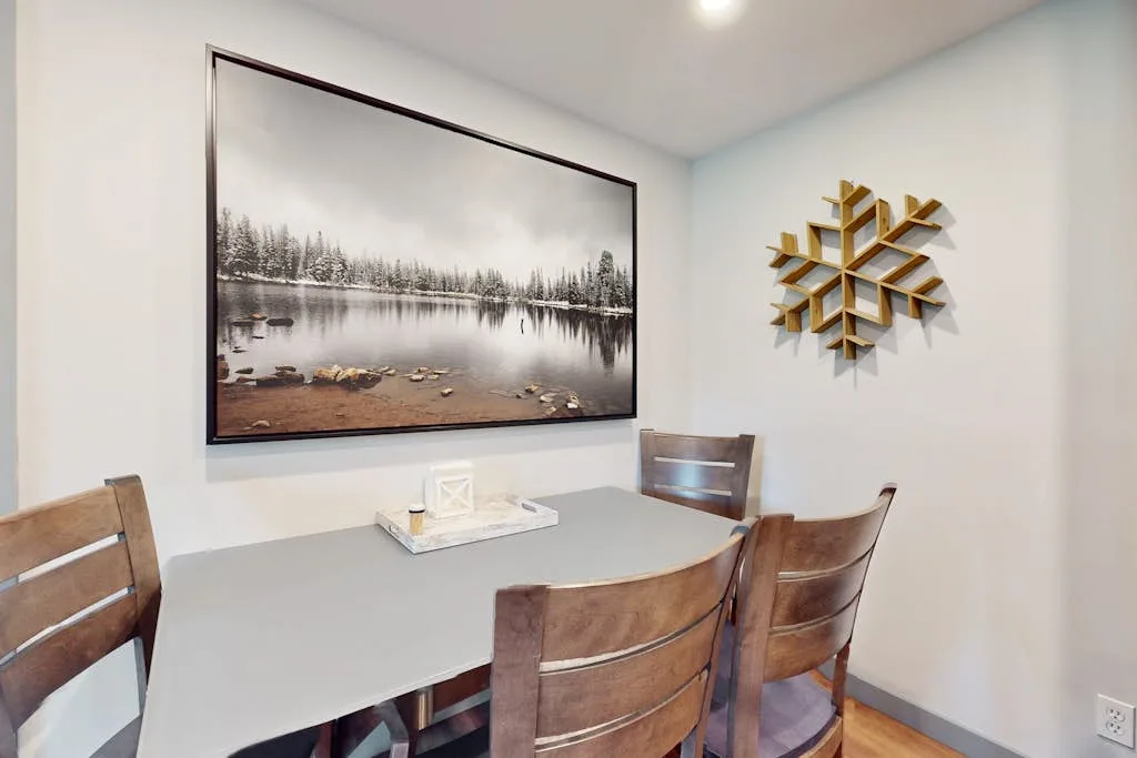 A dining area with a table, wooden seating, and framed landscape artwork.