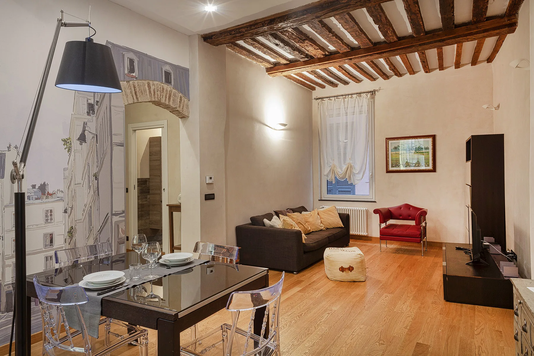 Sala de estar con mesa de comedor, asientos y vigas de madera expuestas en el techo.