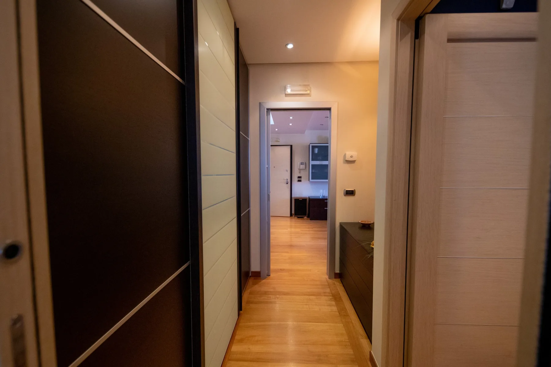 Un pasillo con suelo de madera conduce a una habitación con un escritorio.