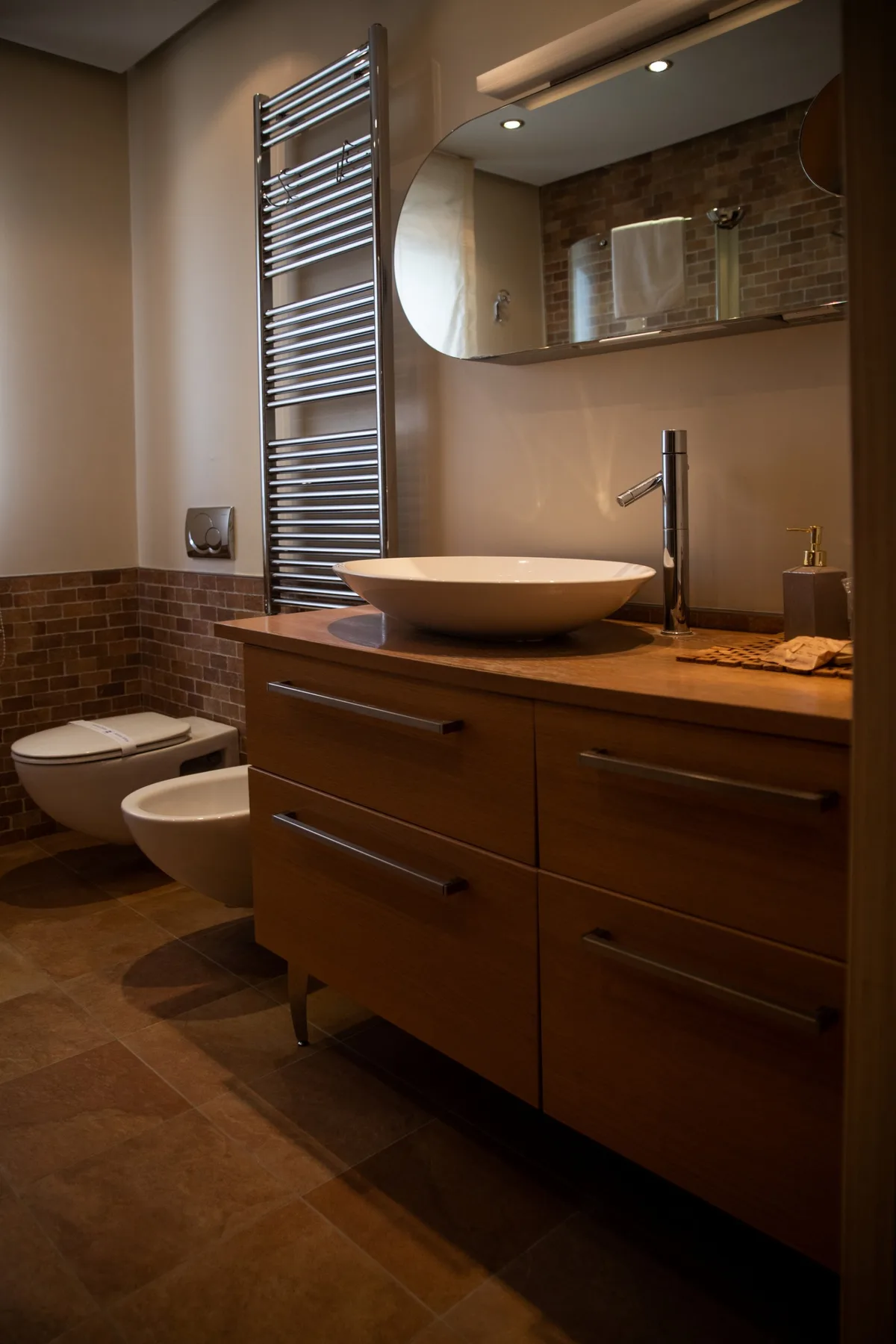 Un baño con mueble de lavabo, lavabo sobre encimera e inodoro.