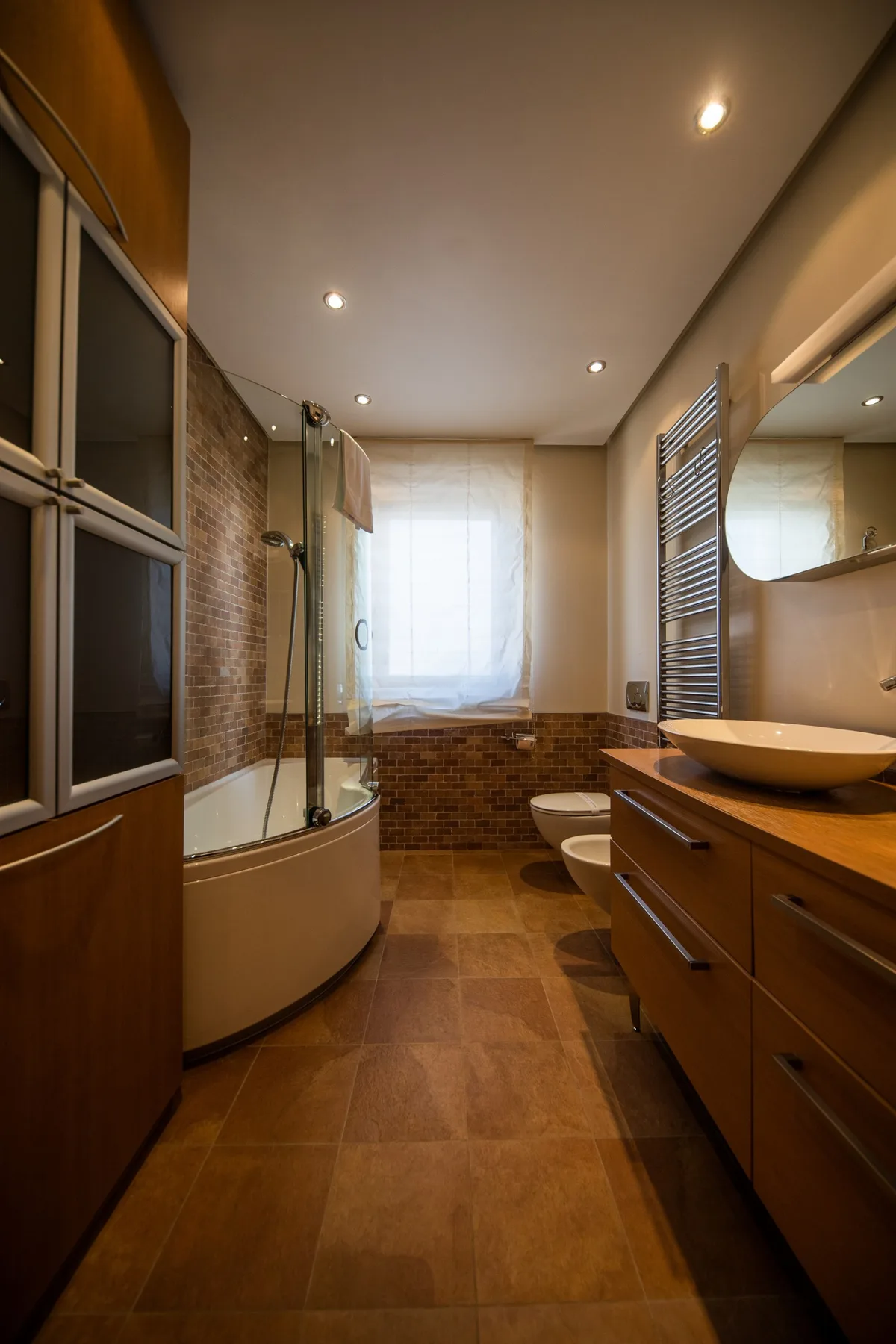 A bathroom with a bathtub, shower, and wooden vanity.