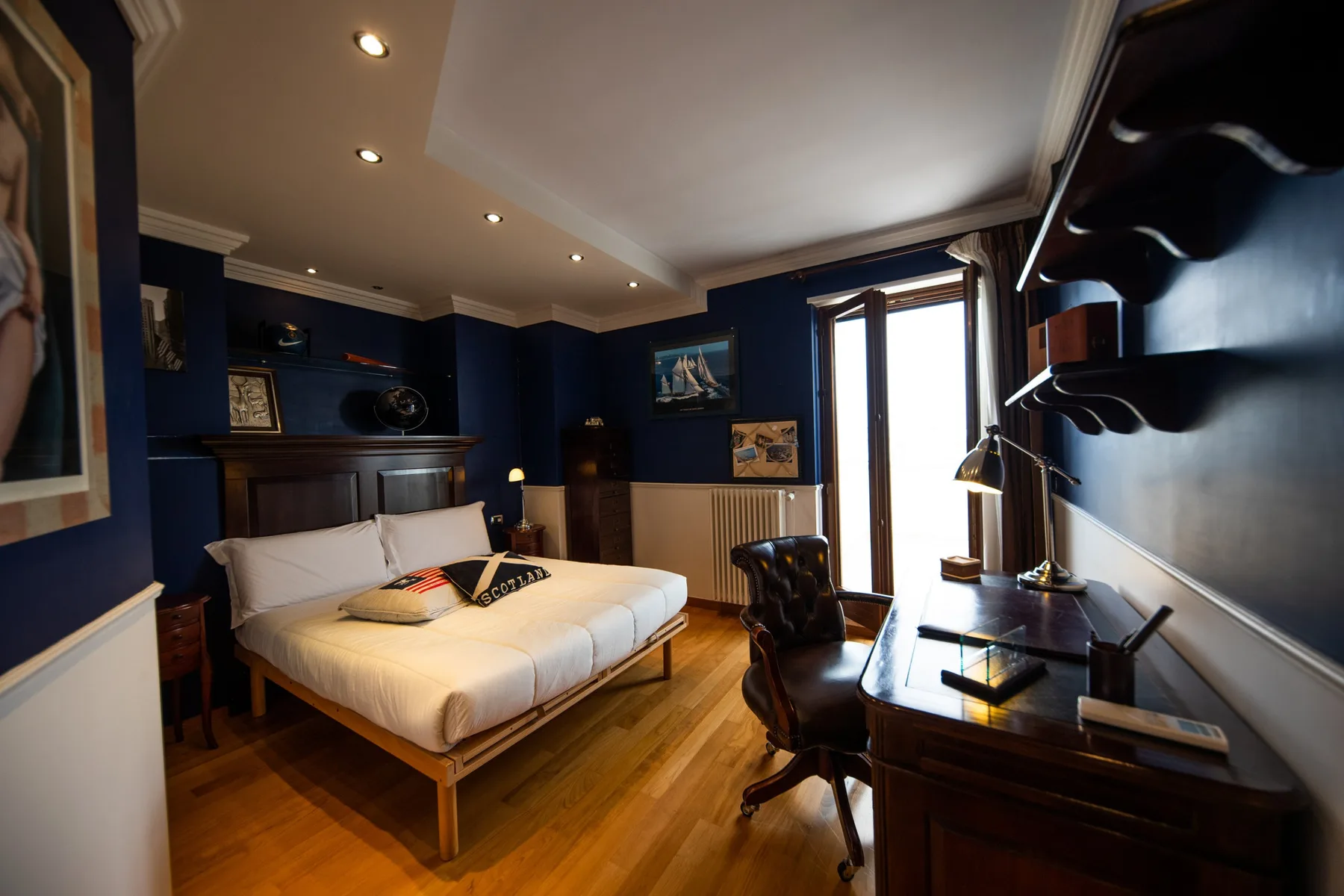 Un dormitorio con una cama junto a un escritorio y una ventana luminosa.