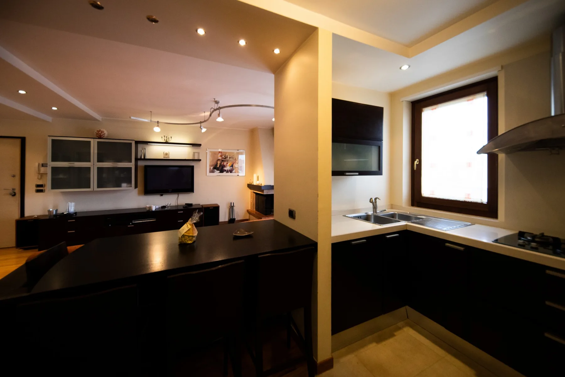 A modern kitchen with dark countertops, a dining counter, and a bright window.