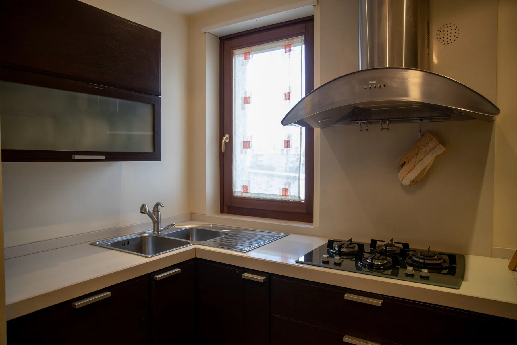 A compact kitchen with dark cabinets, a sink, and a gas cooktop.