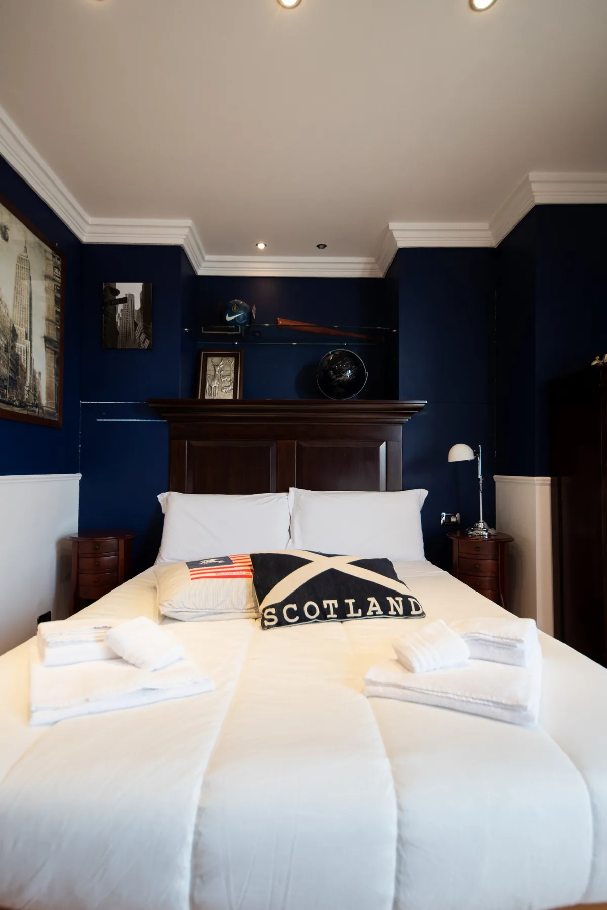 A bedroom with a large bed, white bedding, and dark blue walls.