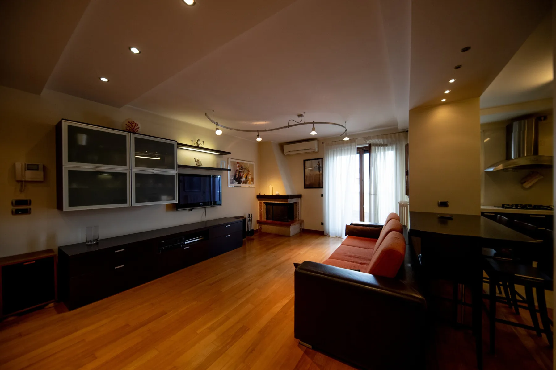 A living room with a long media console, seating, and bright windows.