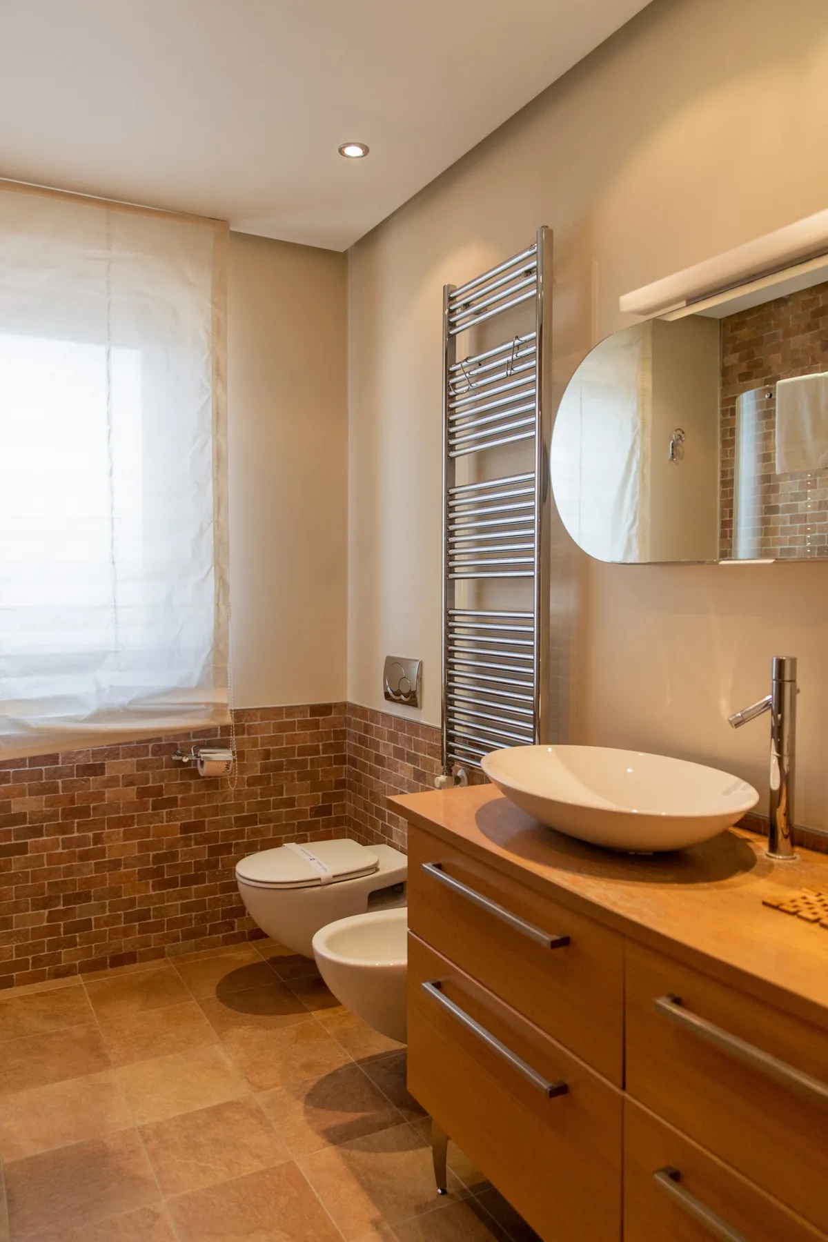 A bathroom with a vessel sink, wall mirror, and tiled walls.