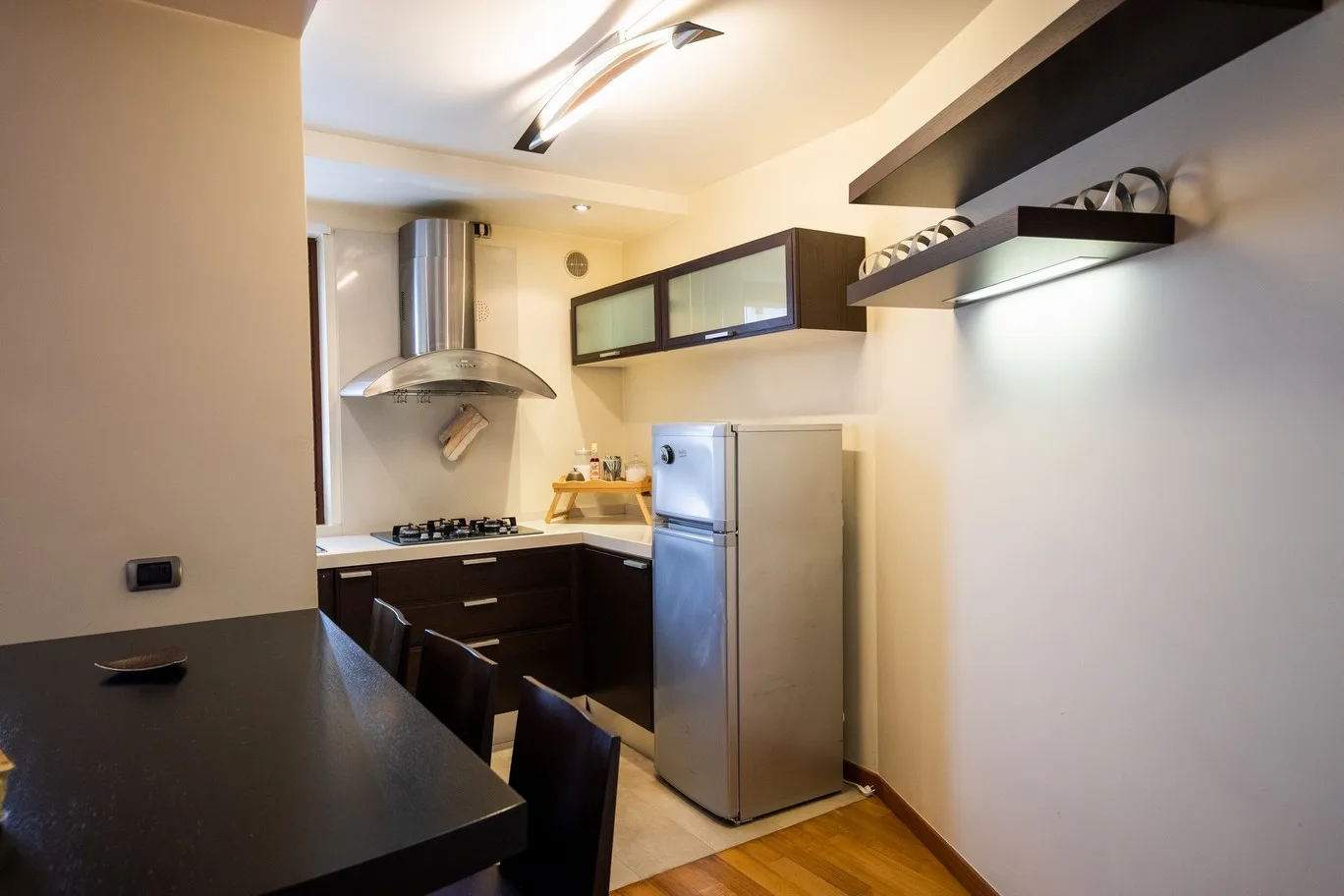 A compact kitchen with dark cabinets, a refrigerator, and a cooktop.