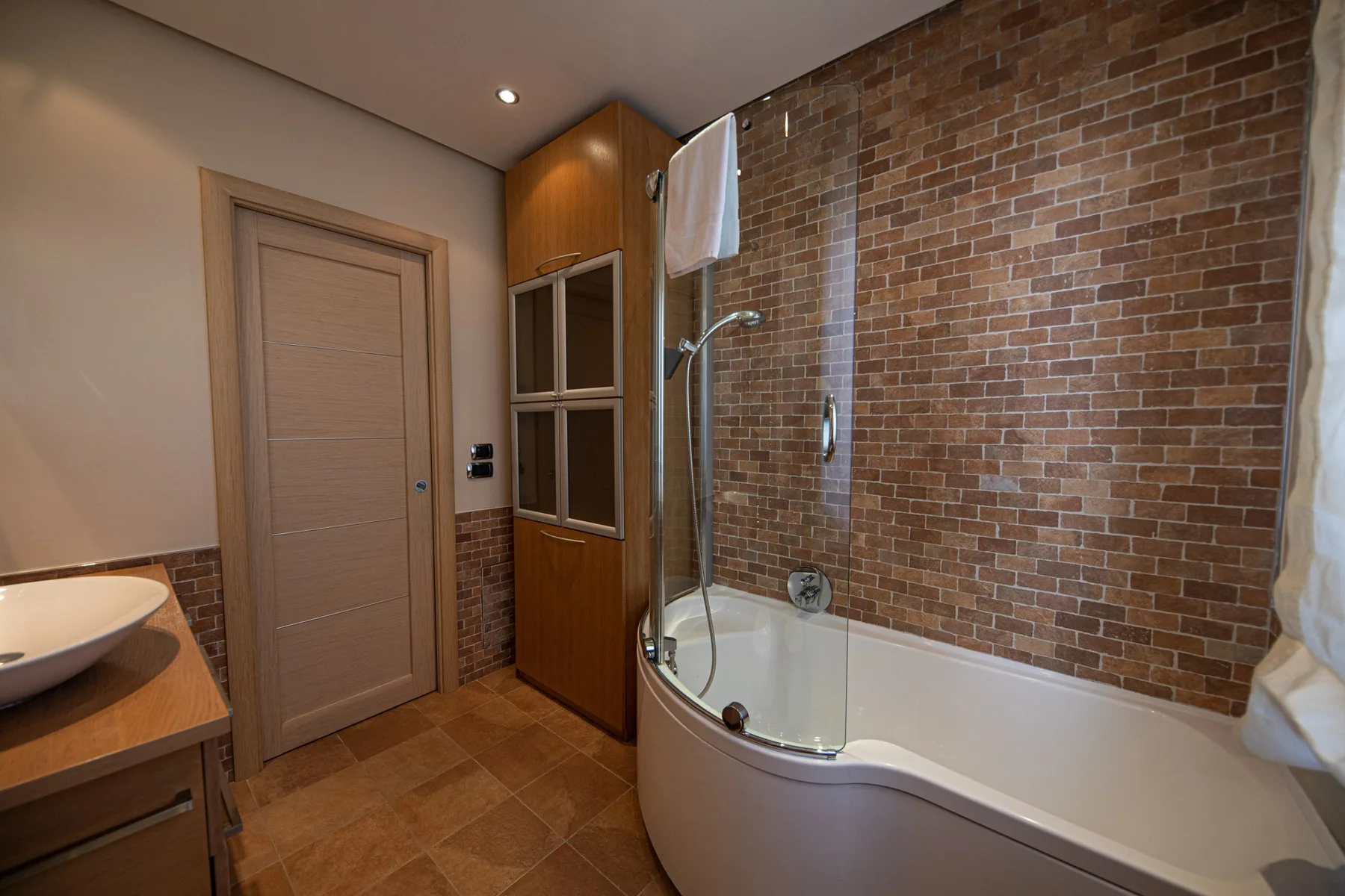 A bathroom with a bathtub and a brick-patterned wall.