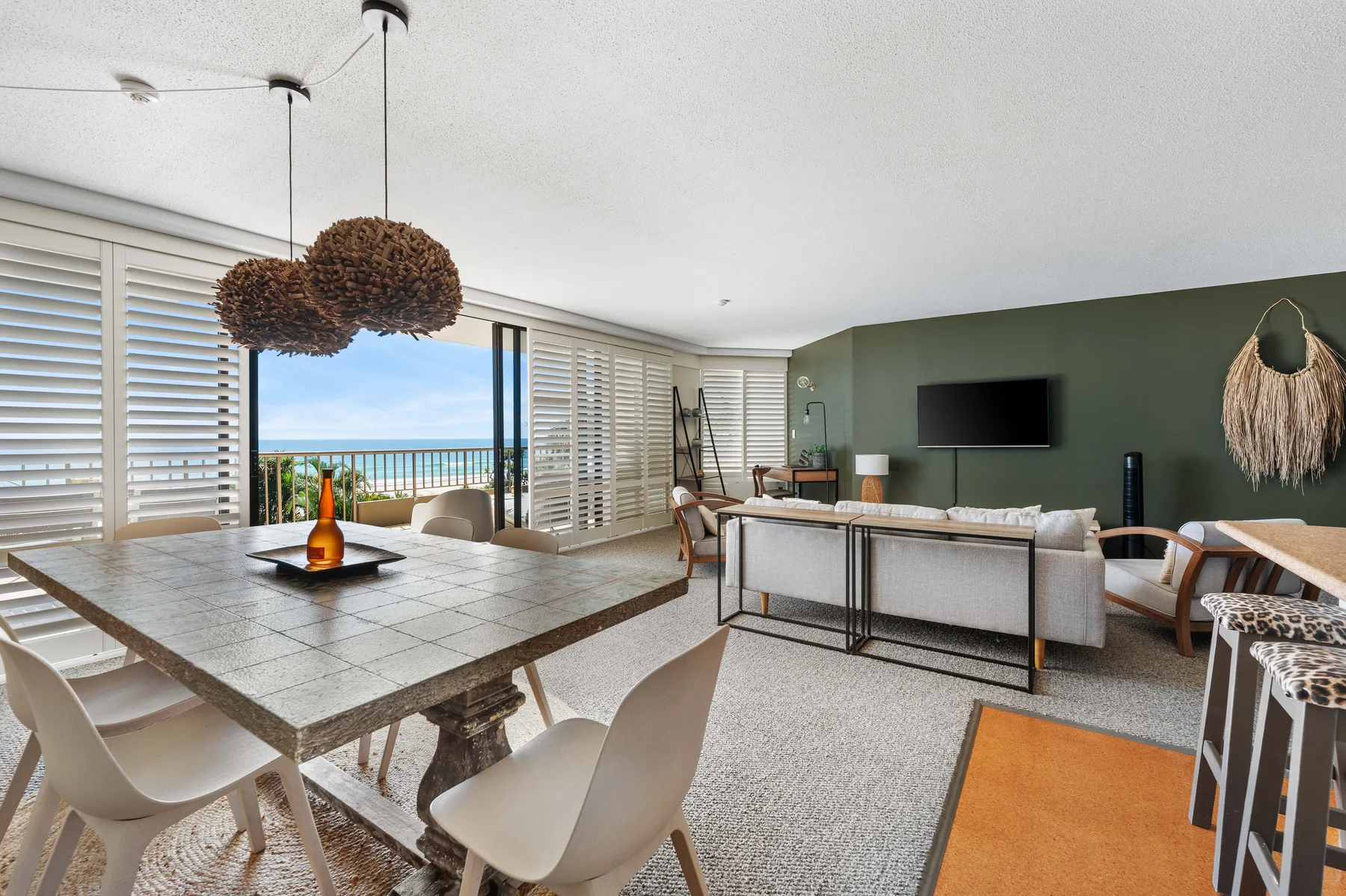 An open-plan living and dining area overlooks the ocean through wide windows.