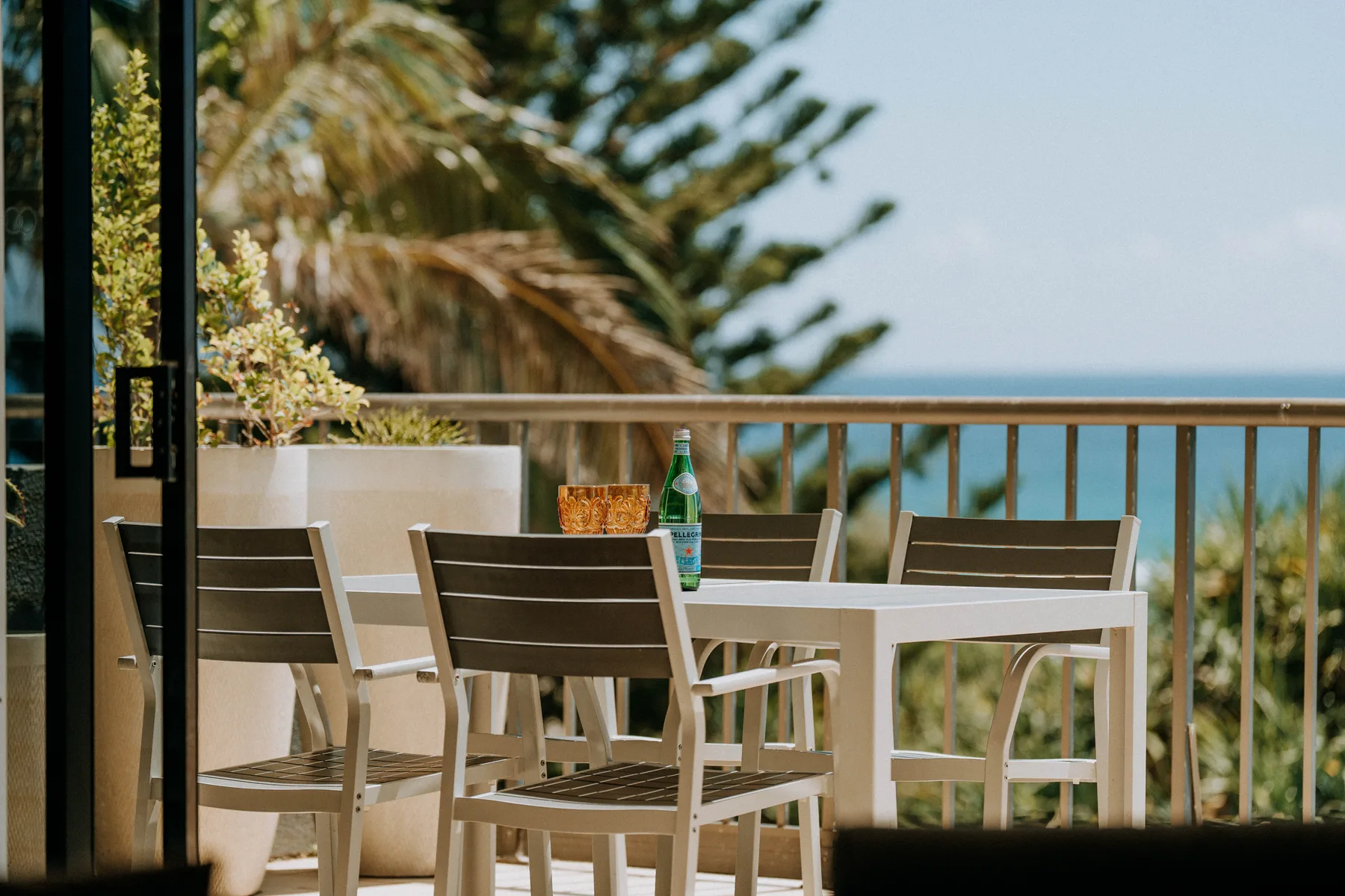 A balcony dining area with outdoor seating and a view of the ocean.