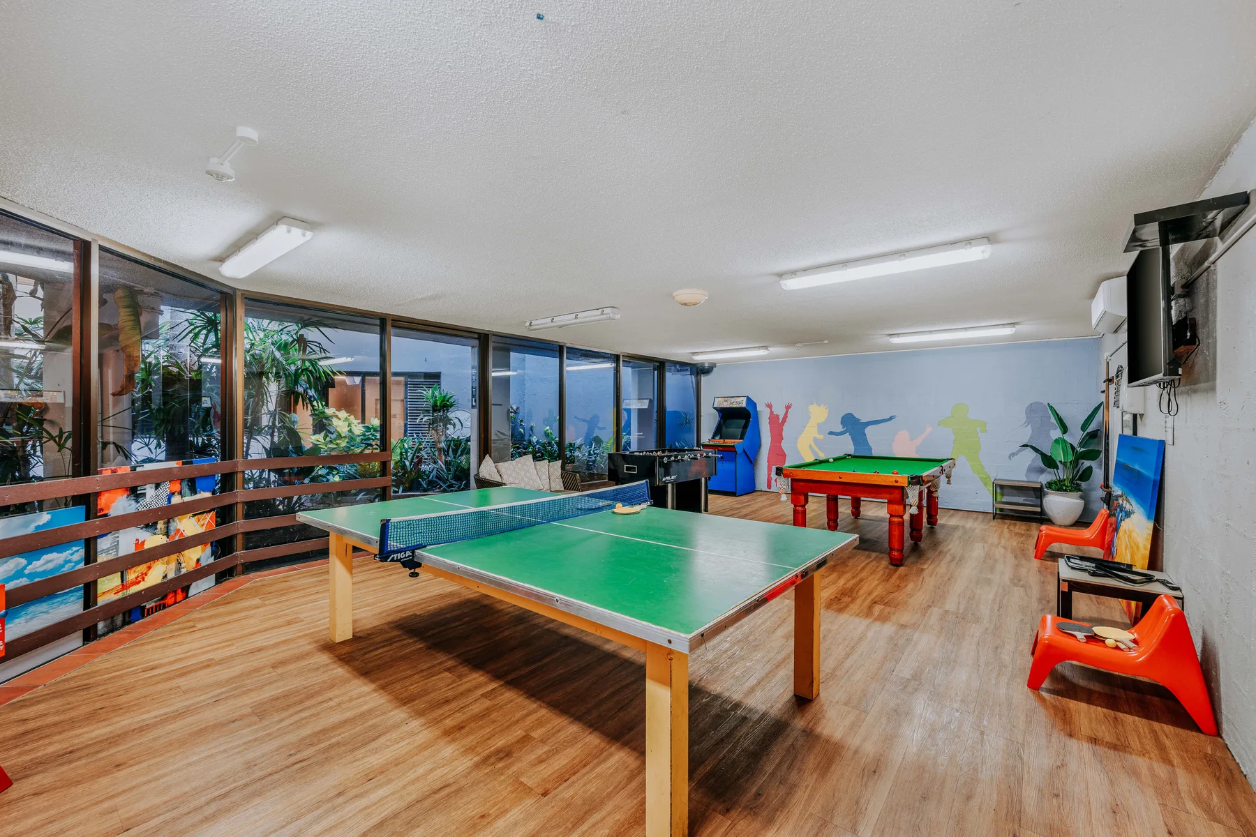 A recreation room with a green table tennis table and a red game table.