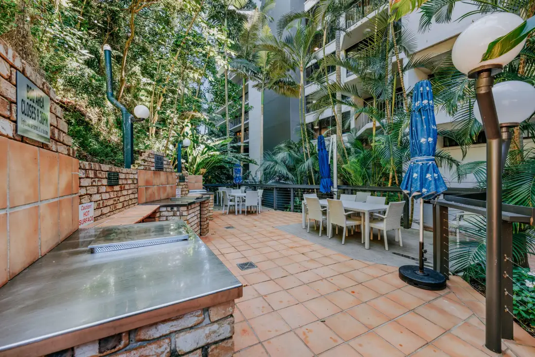An outdoor patio with dining tables and a built-in barbecue area.