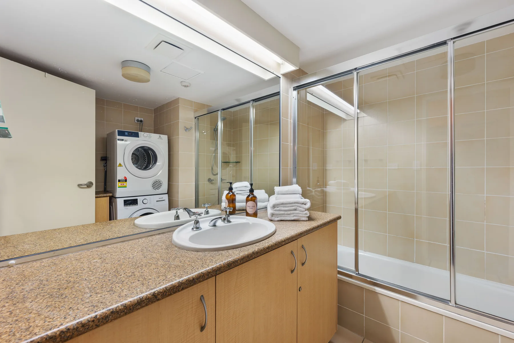 A bathroom vanity faces a large glass-enclosed shower.