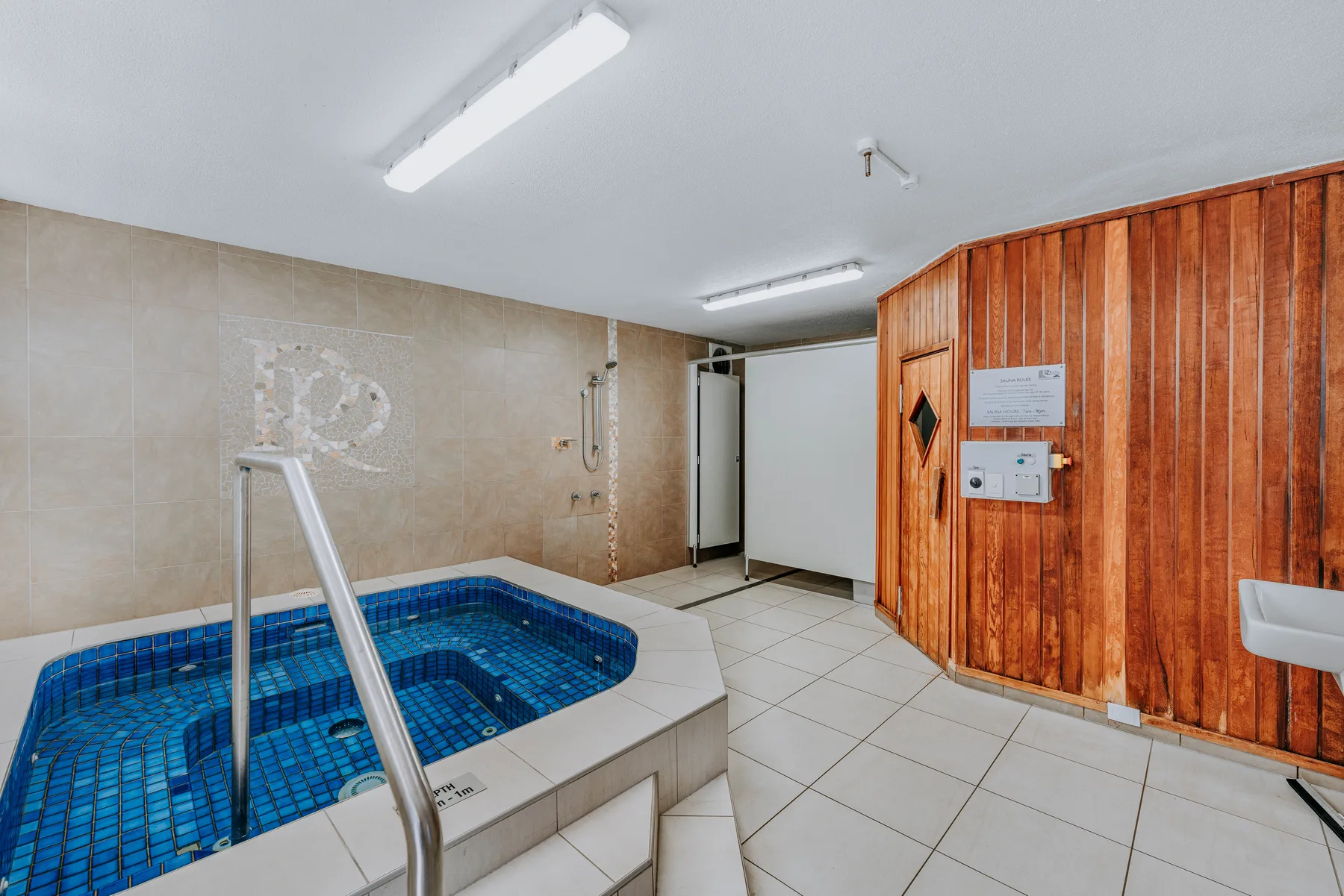 An indoor tiled pool area with blue water and a wooden-paneled wall.