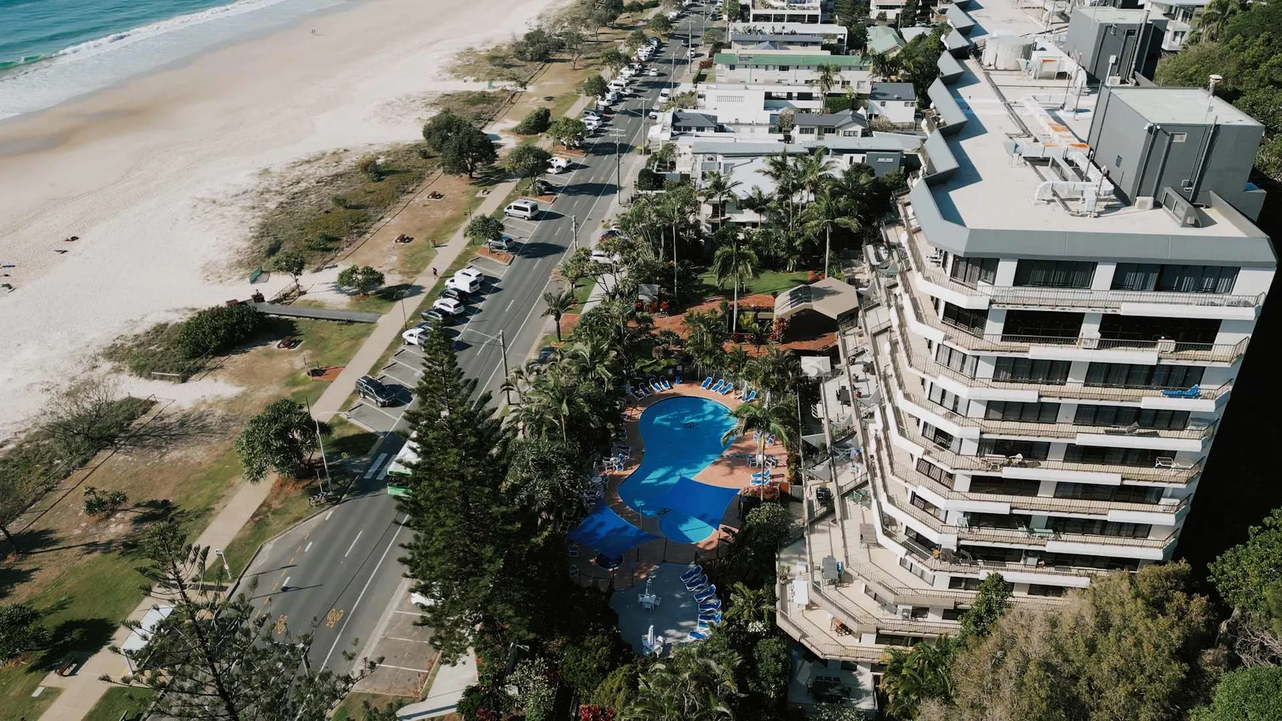 An aerial view of a beachfront resort beside a road and swimming pool.