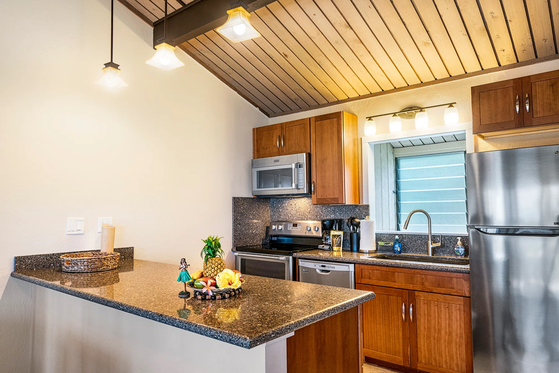 Una cocina con una encimera central, gabinetes de madera y electrodomésticos de acero inoxidable.