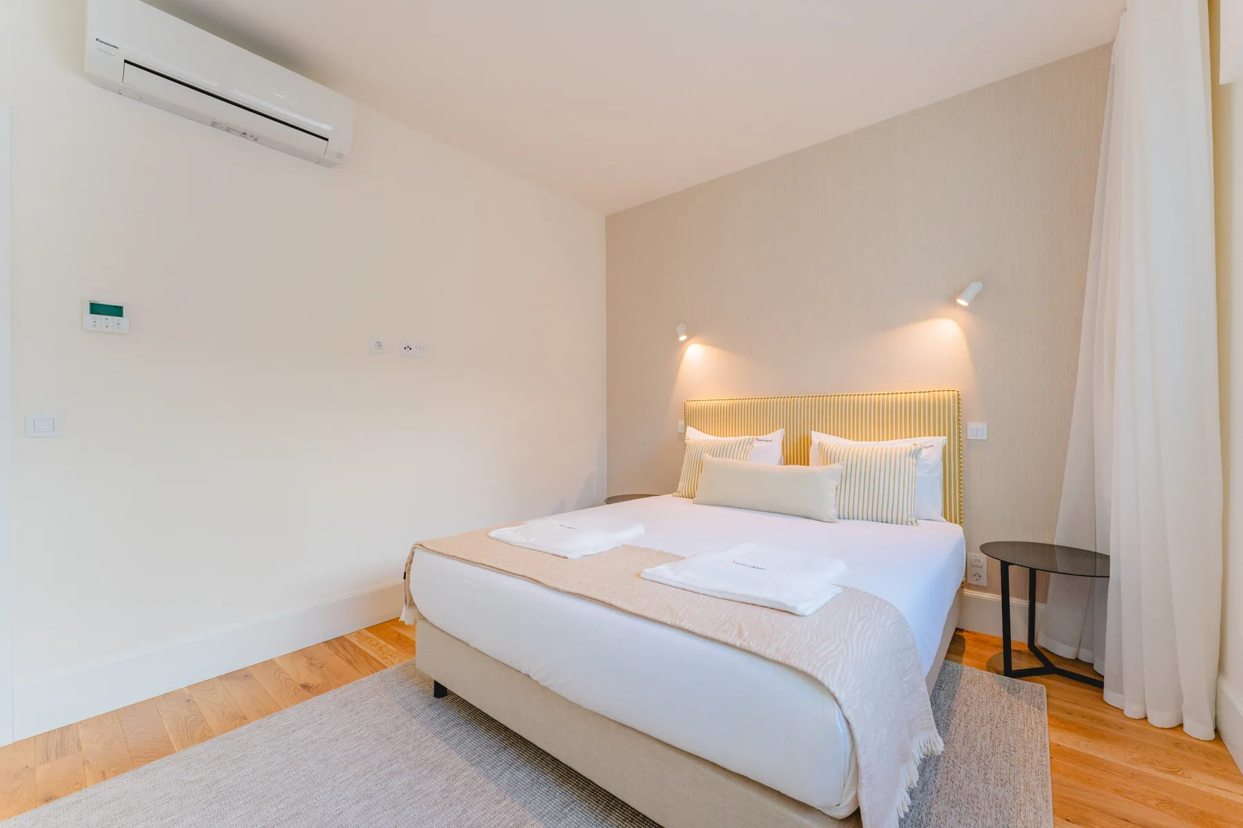 Dormitorio con una cama hecha y luces montadas en la pared.