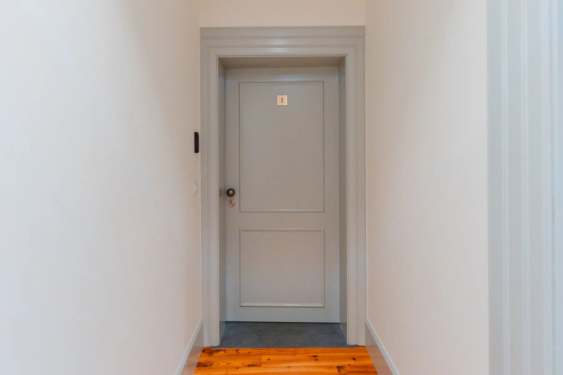 Un pasillo con una puerta cerrada al fondo.