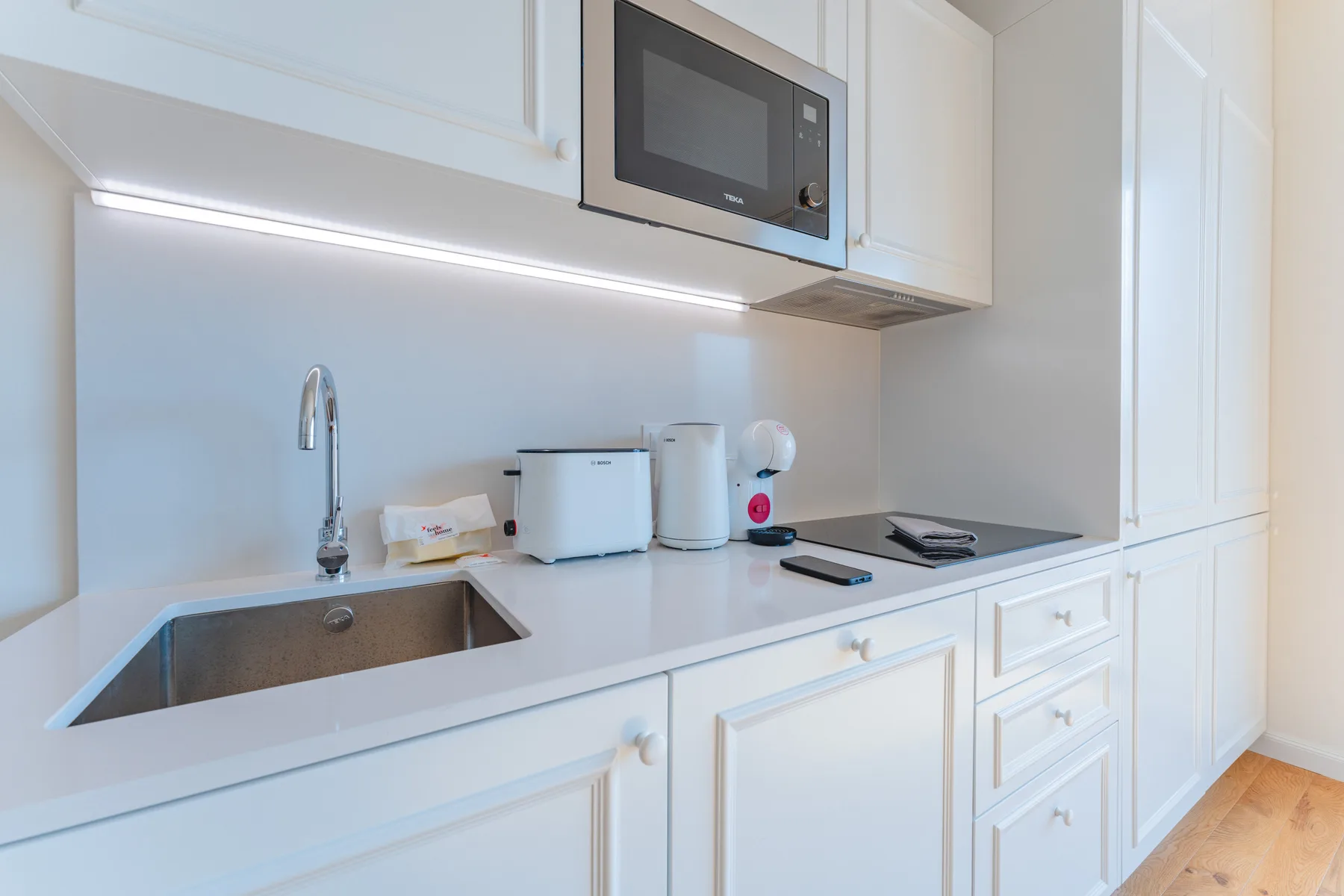 Una cocina luminosa con fregadero, pequeños electrodomésticos y una placa de cocción.