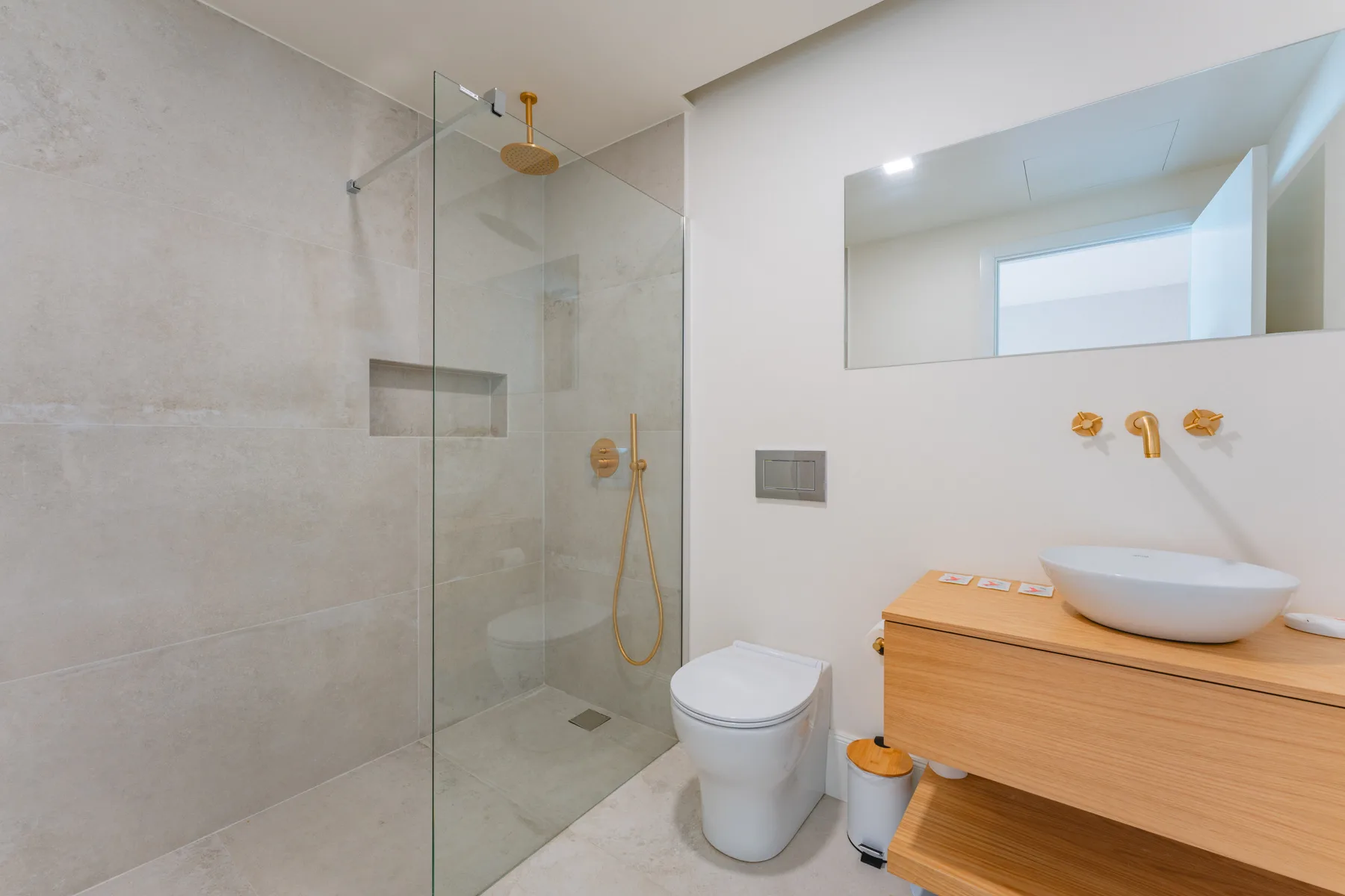 Un baño moderno con ducha de vidrio, inodoro y lavabo sobre encimera.