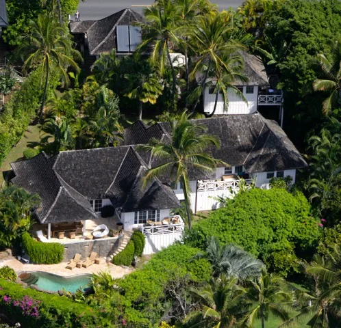 Vista aérea de una propiedad tropical rodeada de palmeras, con una pequeña piscina.