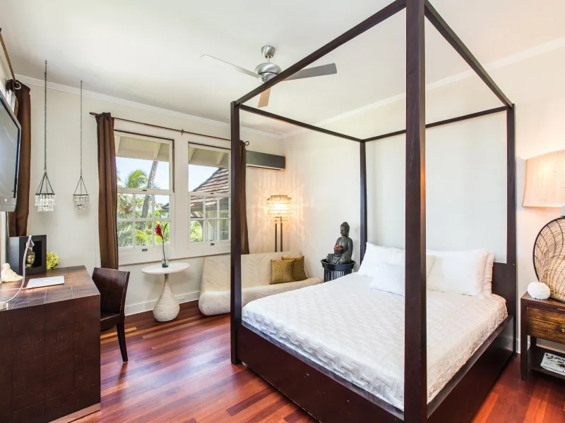 Un dormitorio con cama con dosel y ventanas con vistas a la vegetación.