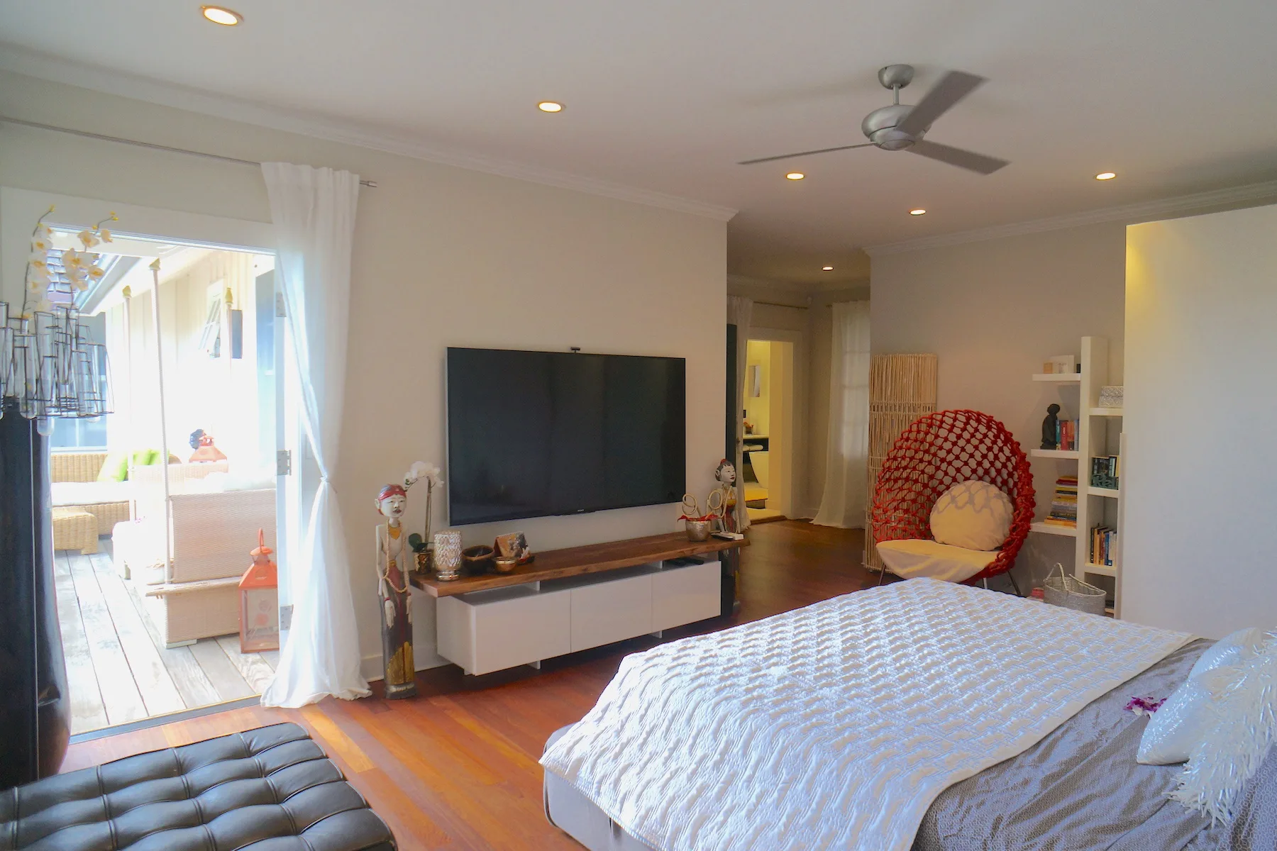 Un dormitorio con una cama, un televisor y una puerta de vidrio con cortinas.