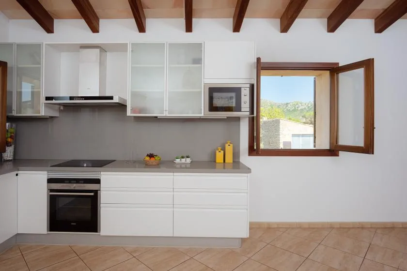 A bright kitchen with white cabinets and an open window.