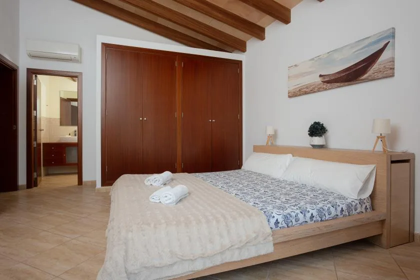 A bedroom with a wooden bed, patterned bedding, and large built-in wardrobes.