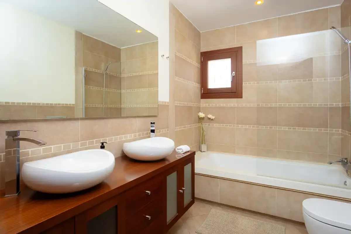 A tiled bathroom with a bathtub and a vanity beneath a large mirror.