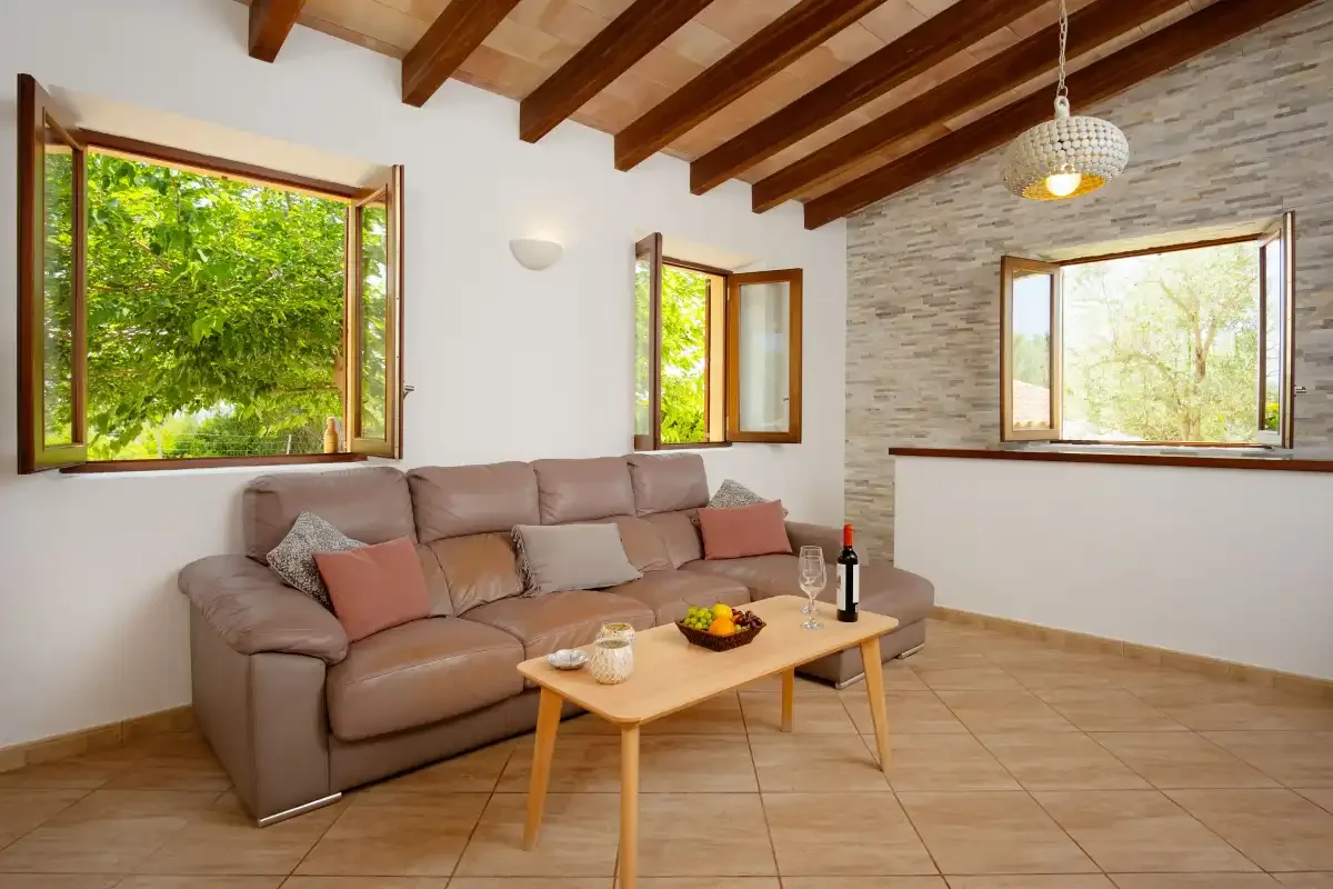 A living room with seating, a coffee table, and large windows.