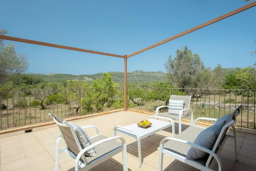 An outdoor terrace with seating and a view of green hills.