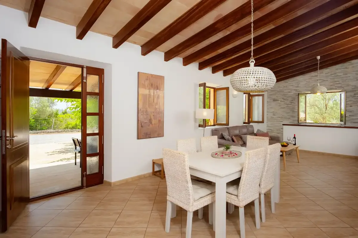 A dining and living room with a table beneath exposed wooden ceiling beams.