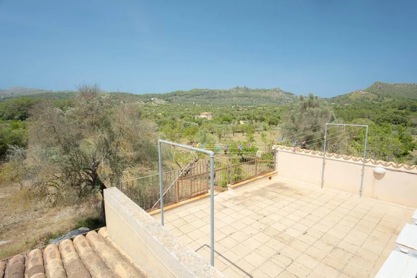 A tiled outdoor terrace overlooks green hills and scattered trees.