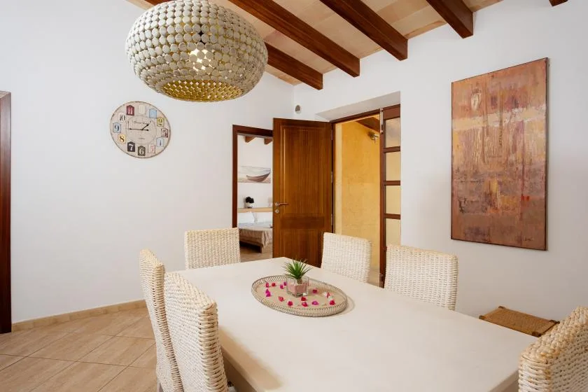 A dining area with a white table, woven seating, and exposed ceiling beams.