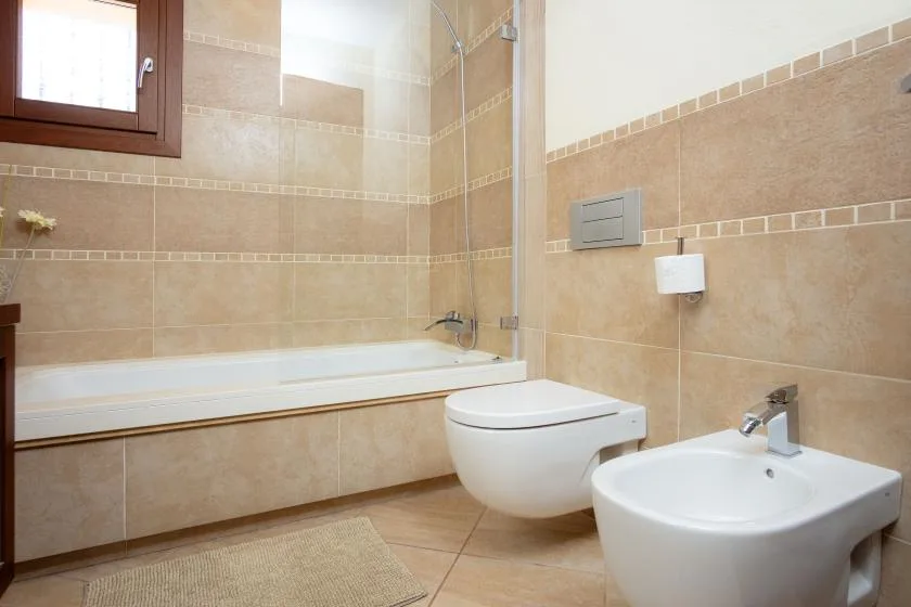 A tiled bathroom with a bathtub, toilet, and sink.