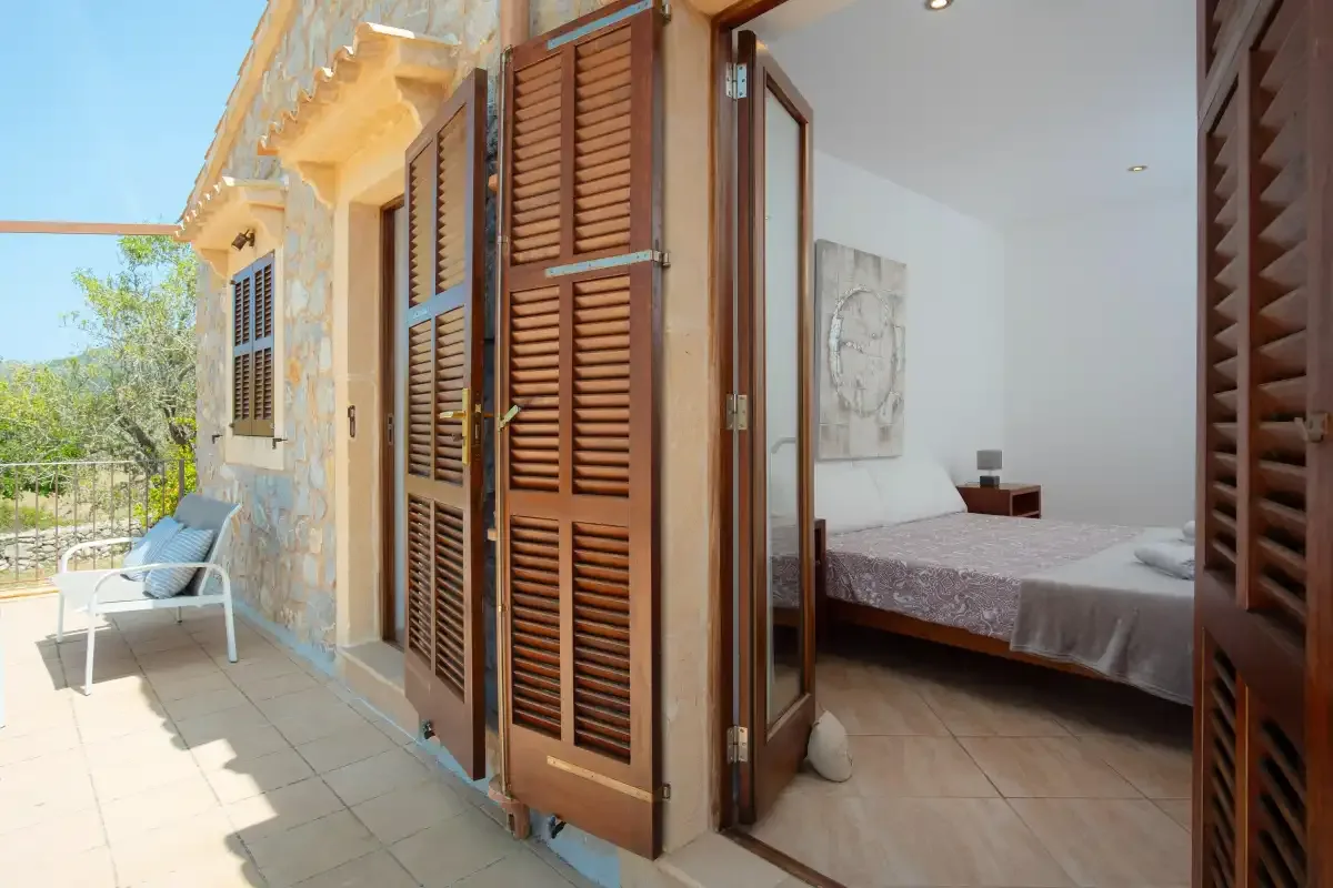 A bedroom opens onto a tiled terrace with outdoor seating.