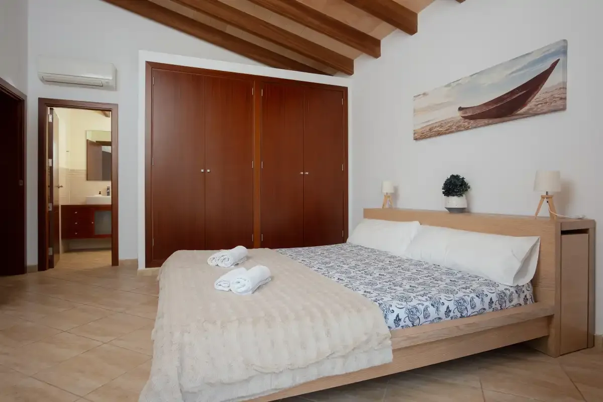 A bedroom with a wooden bed, patterned bedding, and built-in wardrobes.