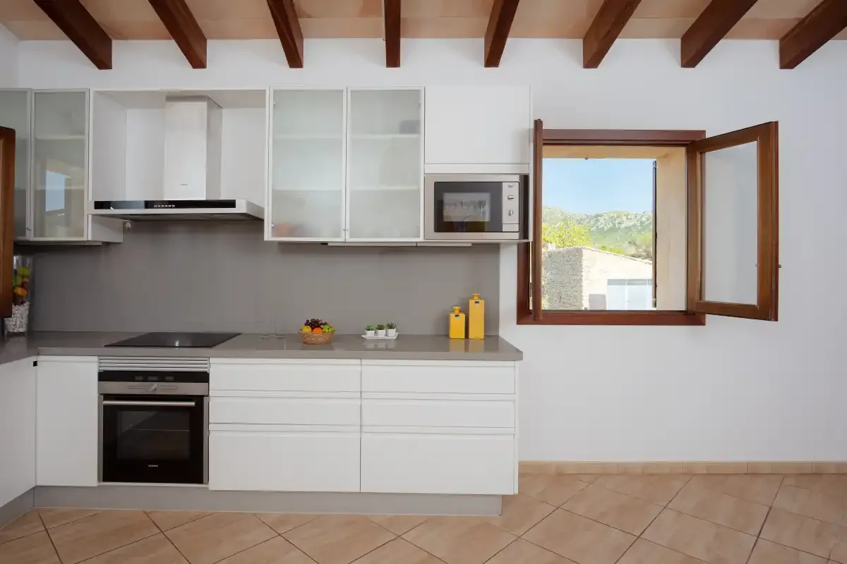 A bright kitchen with white cabinets and an open window.