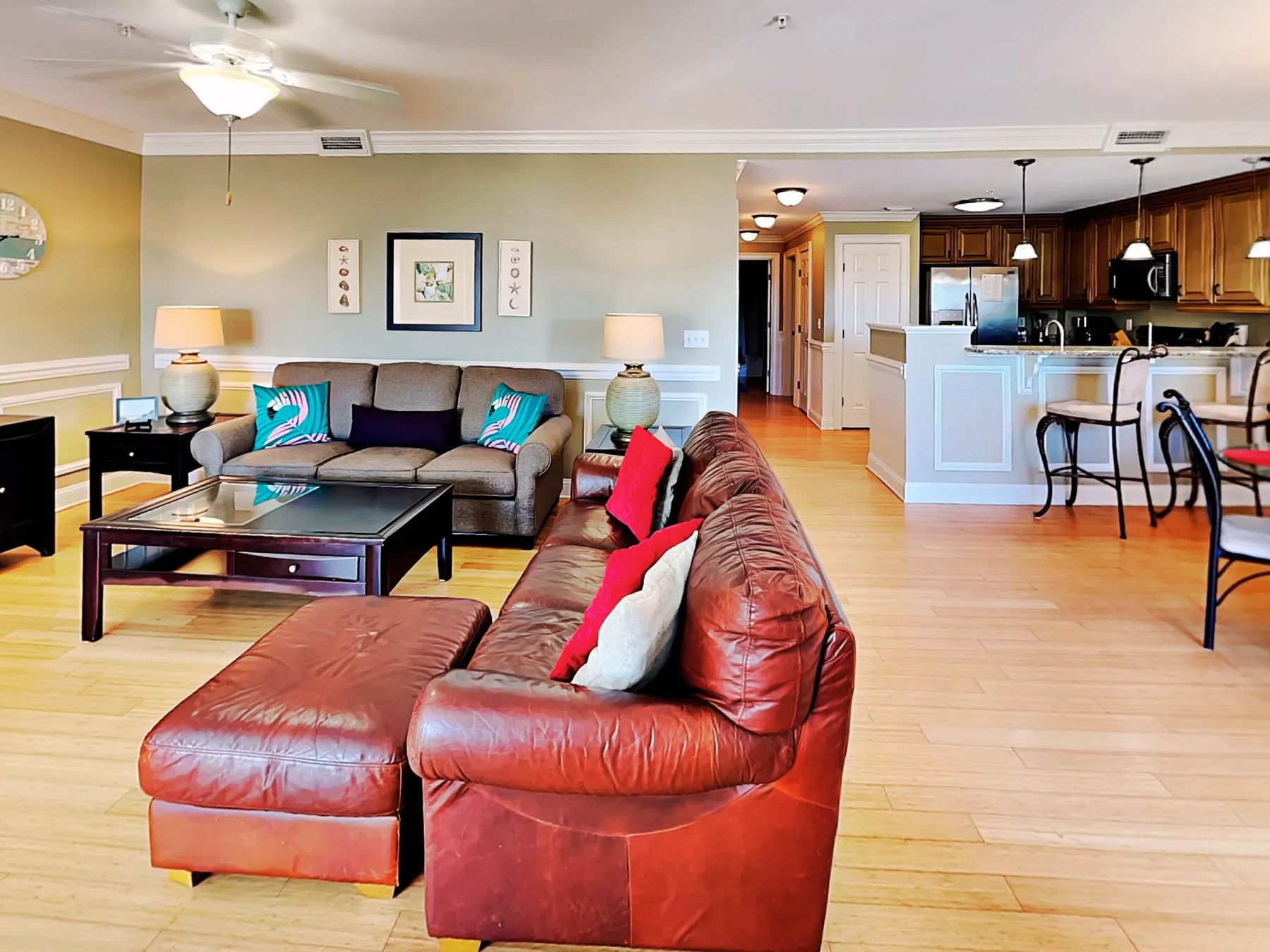 A living room opens into a kitchen and dining area, with seating around a coffee table.
