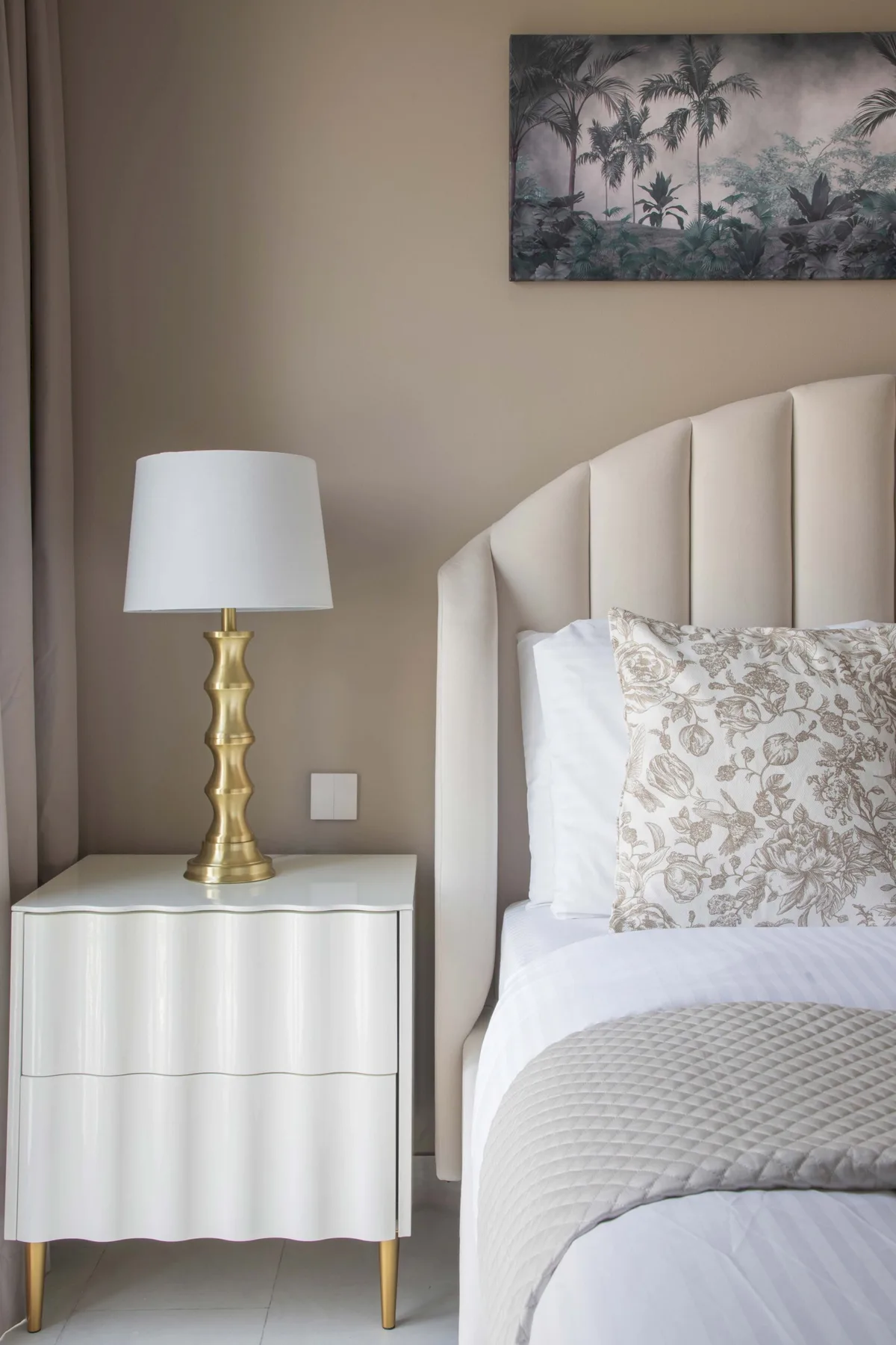 Un dormitorio con una cama bien tendida, una mesita de noche y una lámpara.