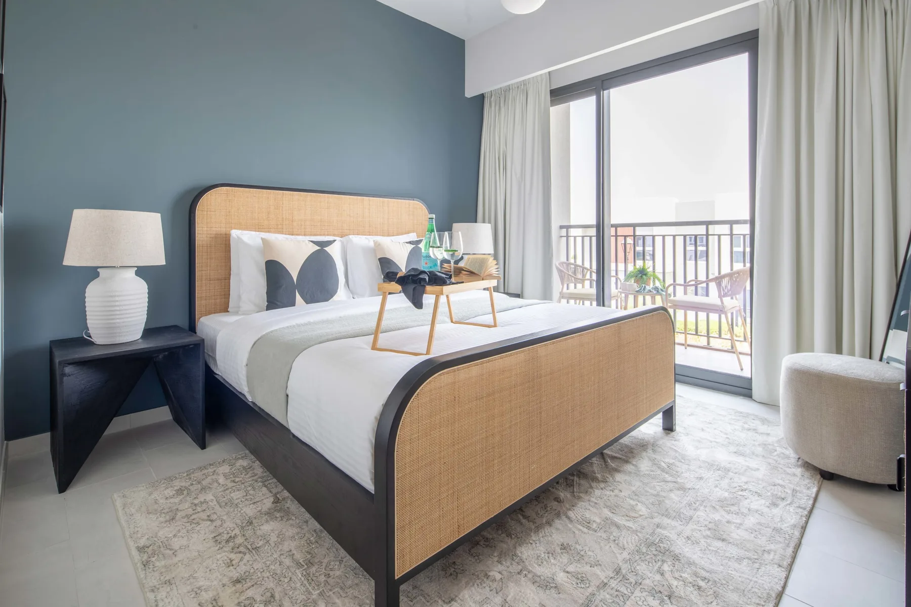 Un dormitorio luminoso tiene una cama junto a una gran ventana con cortinas.