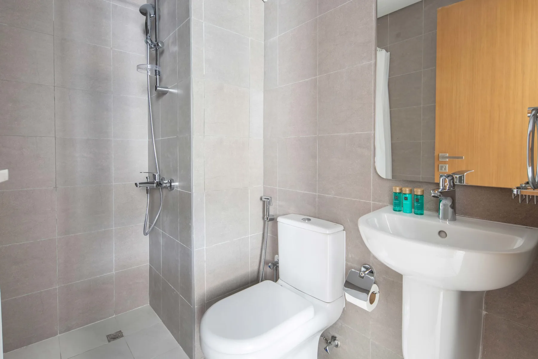 Un baño con azulejos, ducha, inodoro y lavabo.