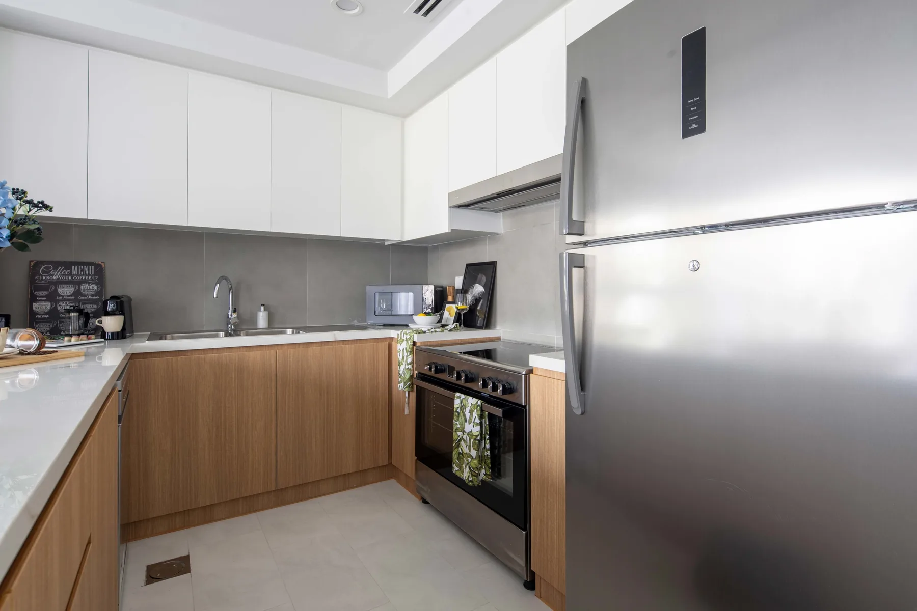 Una cocina moderna con gabinetes blancos, gabinetes inferiores de madera y electrodomésticos de acero inoxidable.