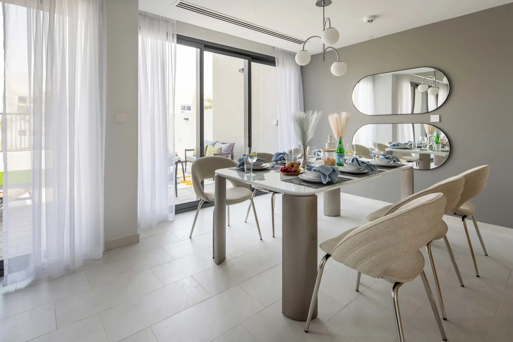 Un comedor luminoso con una mesa preparada para comer junto a grandes ventanales.
