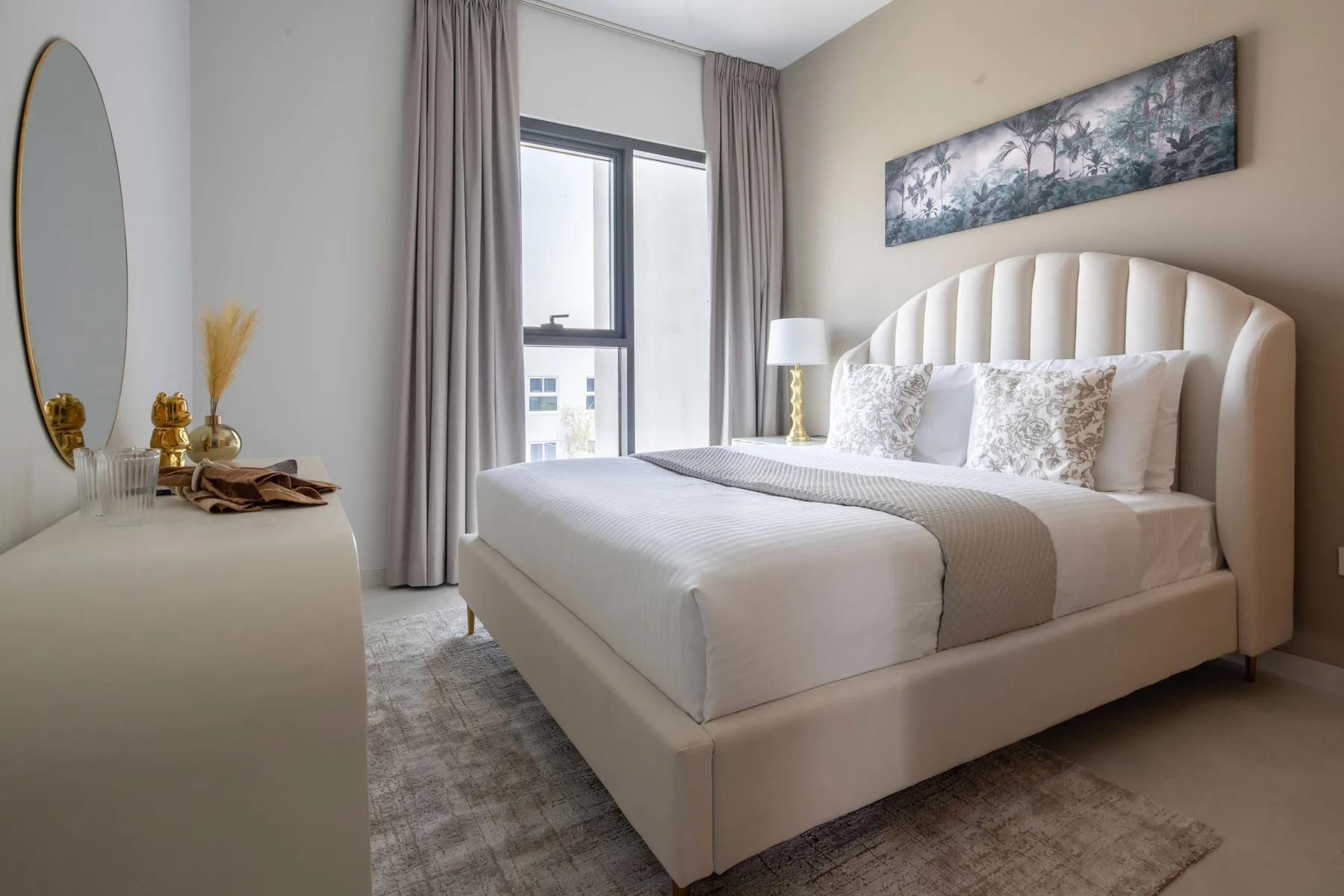 Un dormitorio con una cama bien tendida junto a una ventana alta.