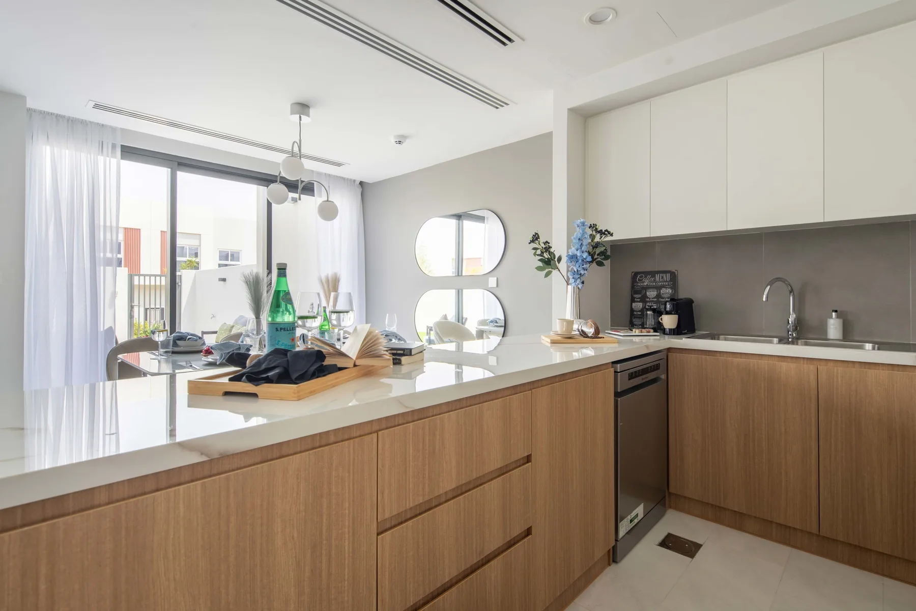 Una luminosa cocina y comedor de concepto abierto, con una isla larga y una mesa.
