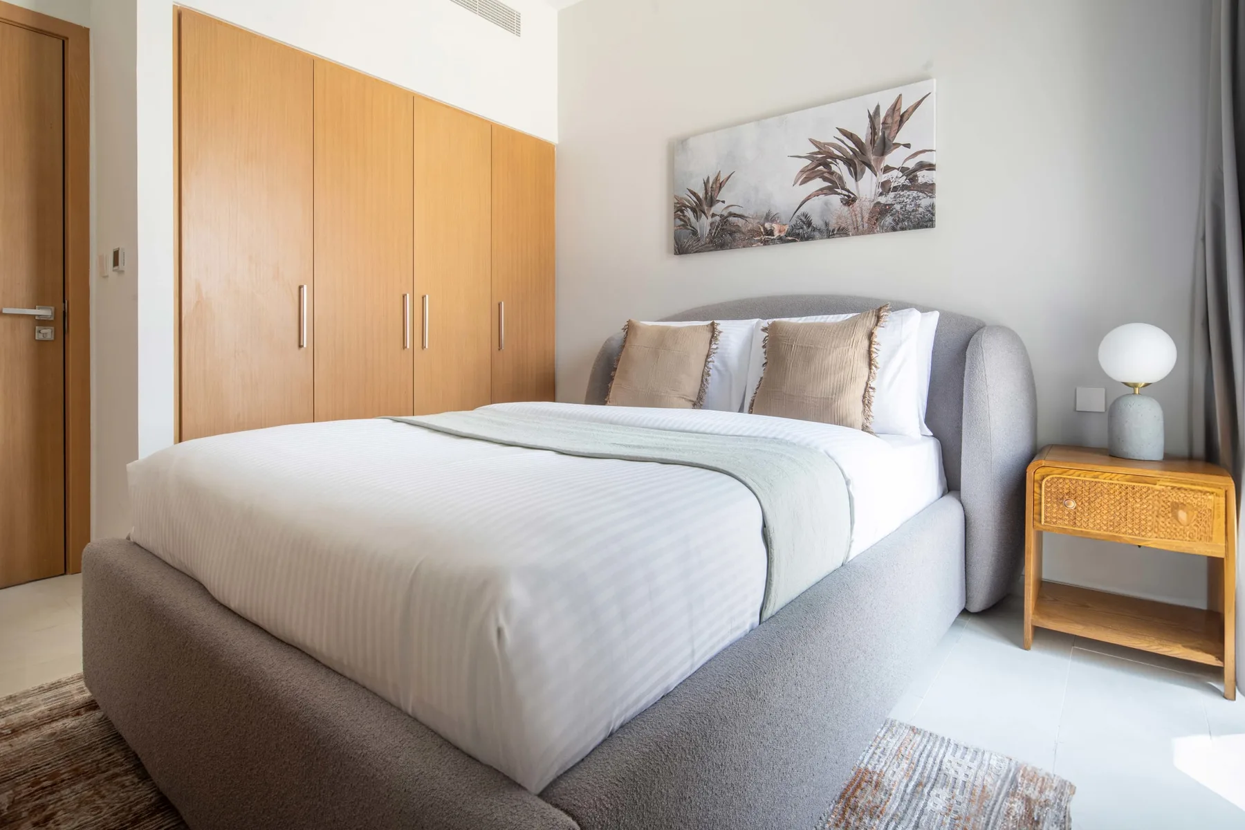 Un dormitorio con una cama bien hecha y un armario de madera.