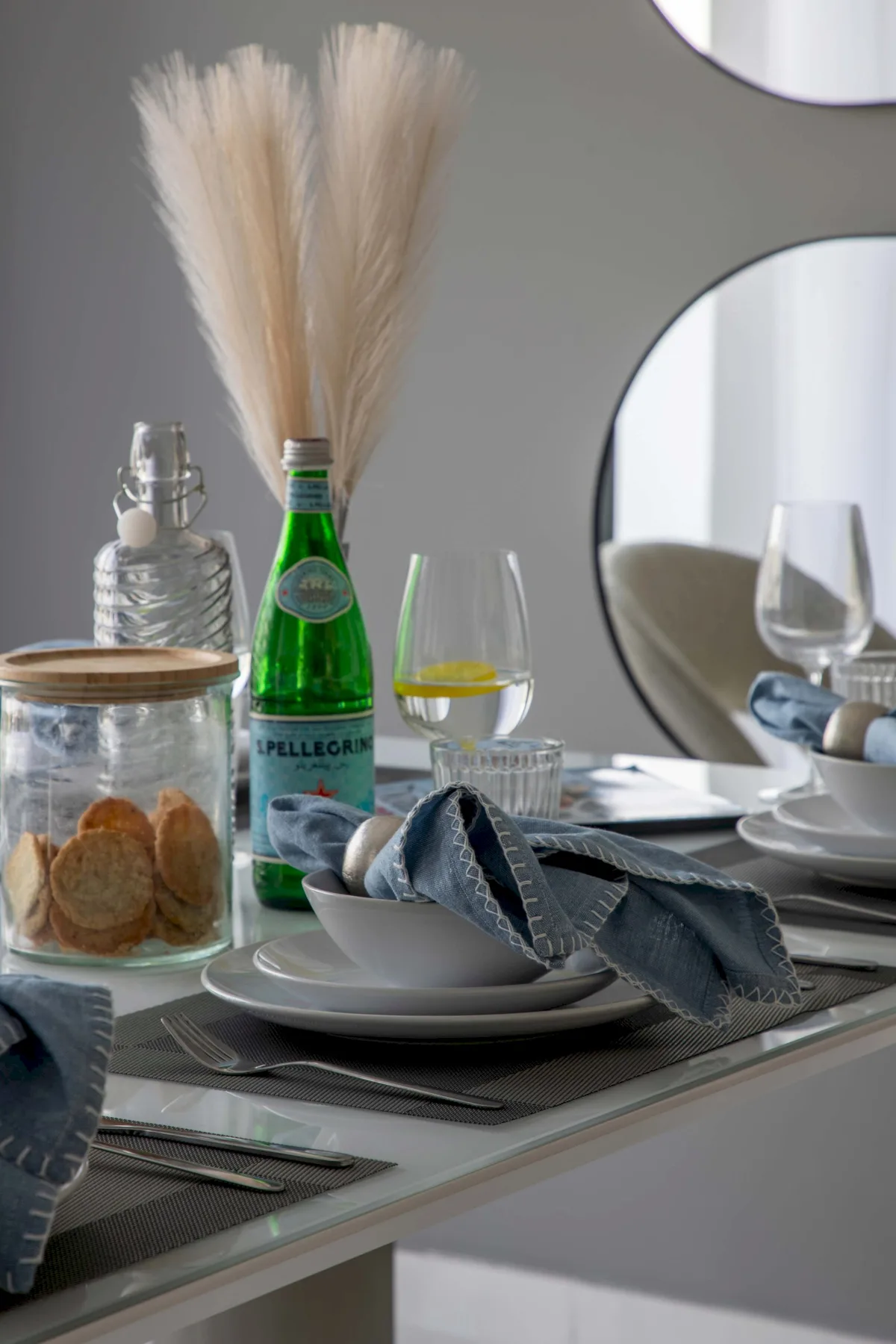 Una mesa de comedor está puesta con platos, copas y una botella de agua con gas.